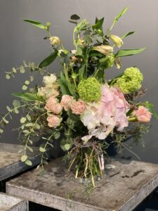 Wilder, natürlich gebundener Blumenstrauß in leuchtenden , Rosa-, creme und grüntönen mit vielfältigen Wiesenblumen, ergänzt durch filigrane Gräser und frisches Grün.