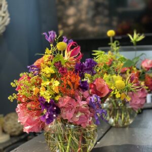 Wilder, natürlich gebundener Blumenstrauß in leuchtenden , Rosa-, lila und pink und gelb Tönen mit vielfältigen Wiesenblumen, ergänzt durch filigrane Gräser und frisches Grün.