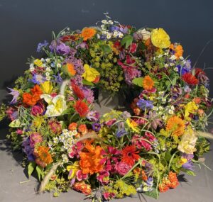 Rundgesteckter Trauerkranz aus verschiedenen bunten Blumen der Saison