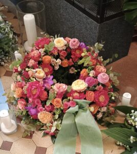 Rundgesteckter Trauerkranz aus verschiedenen bunten Blumen der Saison