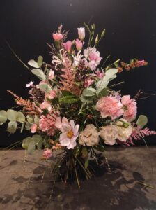 Wilder, natürlich gebundener Blumenstrauß in leuchtenden , Rosa-, creme und grüntönen mit vielfältigen Wiesenblumen, ergänzt durch filigrane Gräser und frisches Grün.