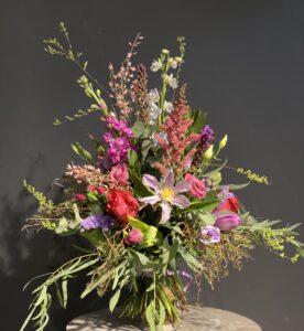 Wilder, natürlich gebundener Blumenstrauß in leuchtenden , Rosa-, lila und pinktönen mit vielfältigen Wiesenblumen, ergänzt durch filigrane Gräser und frisches Grün.