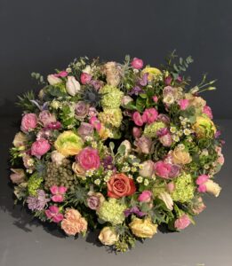 Rundgesteckter Trauerkranz aus verschiedenen bunten Blumen der Saison