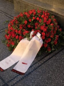 Rundgesteckter Trauerkranz aus roten Rosen und twas grünen Blättern