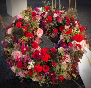Rundgesteckter Trauerkranz aus verschiedenen bunten Blumen der Saison