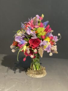 Rund gebundener Blumenstrauß in leuchtenden , Rosa-, rot und pinktönen mit vielfältigen Wiesenblumen, ergänzt durch filigrane Gräser und frisches Grün.