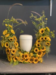 Eine Urne steht in einem Bogen aus Sonnenblumen