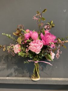kleiner natürlich gebundener Blumenstrauß in leuchtenden , Rosa-, creme und pinktönen mit vielfältigen Wiesenblumen, ergänzt durch filigrane Gräser und frisches Grün.