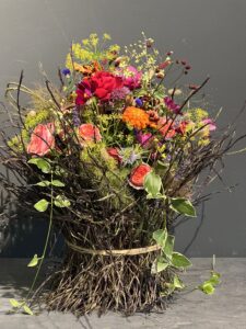 bunte Blumenbündelung die um eine Urne herumgearbeitet ist