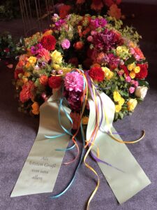 Rundgesteckter Trauerkranz aus verschiedenen bunten Blumen der Saison