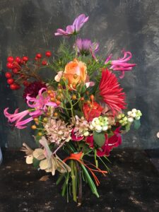 Natürlich gebundener Blumenstrauß in leuchtenden , bunten Farben, mit vielfältigen Wiesenblumen, ergänzt durch filigrane Gräser und frisches Grün.