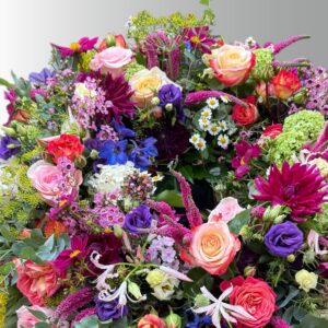 Rundgesteckter Trauerkranz aus verschiedenen bunten Blumen der Saison