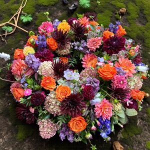 Rundgesteckter Trauerkranz aus verschiedenen bunten Blumen der Saison