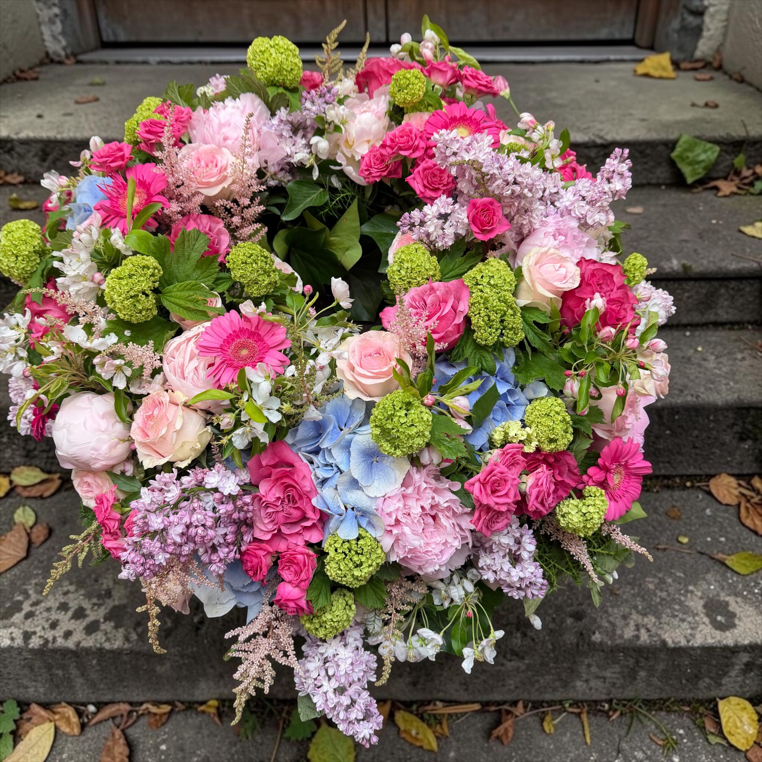 Rundgesteckter Trauerkranz aus verschiedenen bunten Blumen der Saison