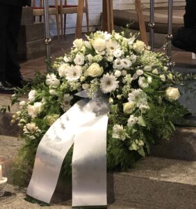 dekorativer Trauerkranz aus weißen Blumen mit weißer Schleife
