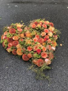 verschieden orange Blumen in Herzform gesteckt