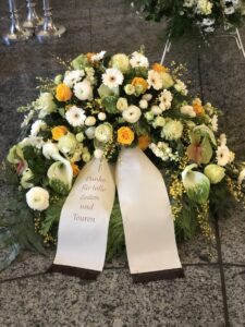 dekorativer Trauerkranz aus weißen und gelben Blumen