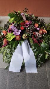 dekorativer Trauerkranz gesteckt aus edlen Blüten mit Trauerschleife