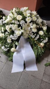 dekorativer Trauerkranz aus weißen Blumen mit Schleife